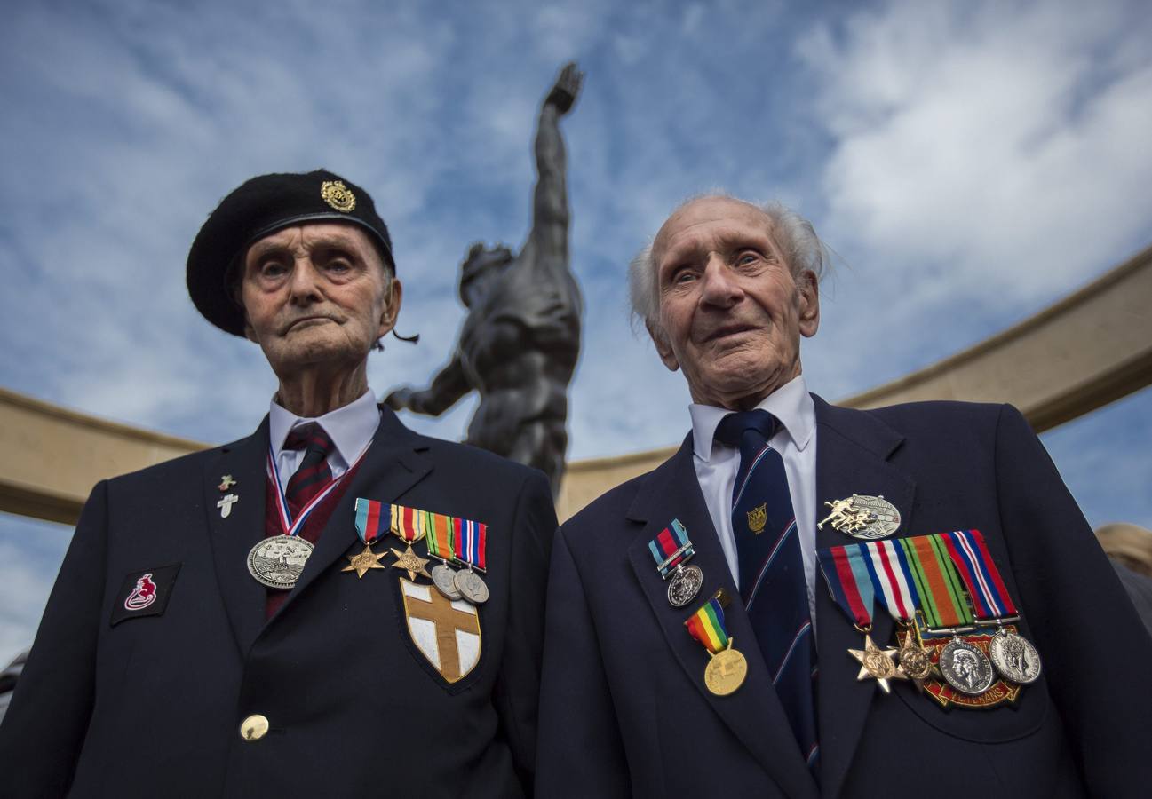 Los veteranos de la Segunda Guerra Mundial, Ronnie Firth, de 94 años, de la unidad de los Ingenieros Reales "Ratas del desierto" (i), y Ernie Covill, de 89 años, de la Armada Real (d), posan bajo el monumento conmemorativo en el cementerio estadounidense en Colleville-Sur-Mer.