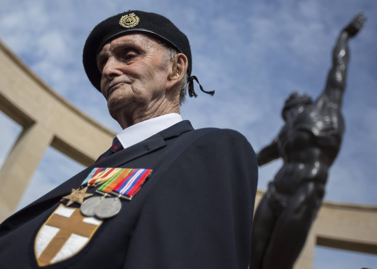 El veterano de la Segunda Guerra Mundial, Ronnie Firth, de 94 años, de la unidad de los Ingenieros Reales "Ratas del desierto", posa bajo el monumento conmemorativo en el cementerio estadounidense en Colleville-Sur-Mer.