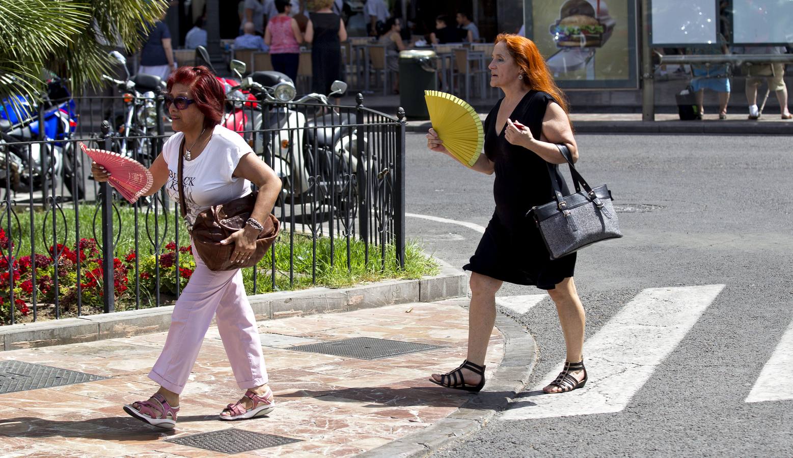 Dos mujeres caminan por la plaza del Ayutnamiento de Valencia mientras se abanican ante el intenso calor.