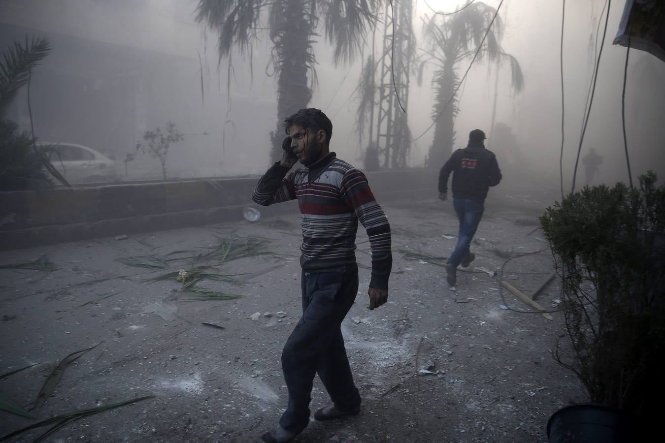 fotografía de la serie ganadora en "Historias" del primer premio de la categoría noticias de actualidad de la 59 edición del World Press Photo, tomada por el fotógrafo Sameer Al-Doumy. La fotografía muestra a un hombre herido caminando entre el humo causado por los bombardeos efectuados sobre la región de Ghouta, en la zona rebelde de Siria, el 9 de diciembre de 2015.