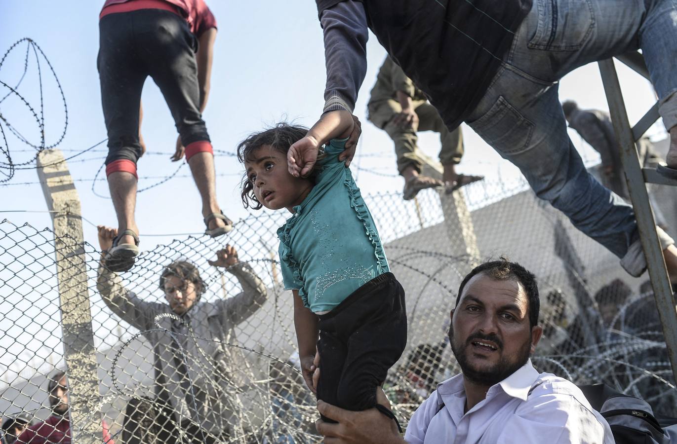 Fotografía de la serie ganadora del tercer premio en "Historias" de la categoría de noticias puntuales de la 59 edición del World Press Photo, tomada por el fotógrafo turco Bulent Kilic. La fotografía muestra a varias familias sirias intentando cruzar ilegalmente la frontera turca cerca de la ciudad de Akçakale (Turquía) el 14 de junio de 2015.