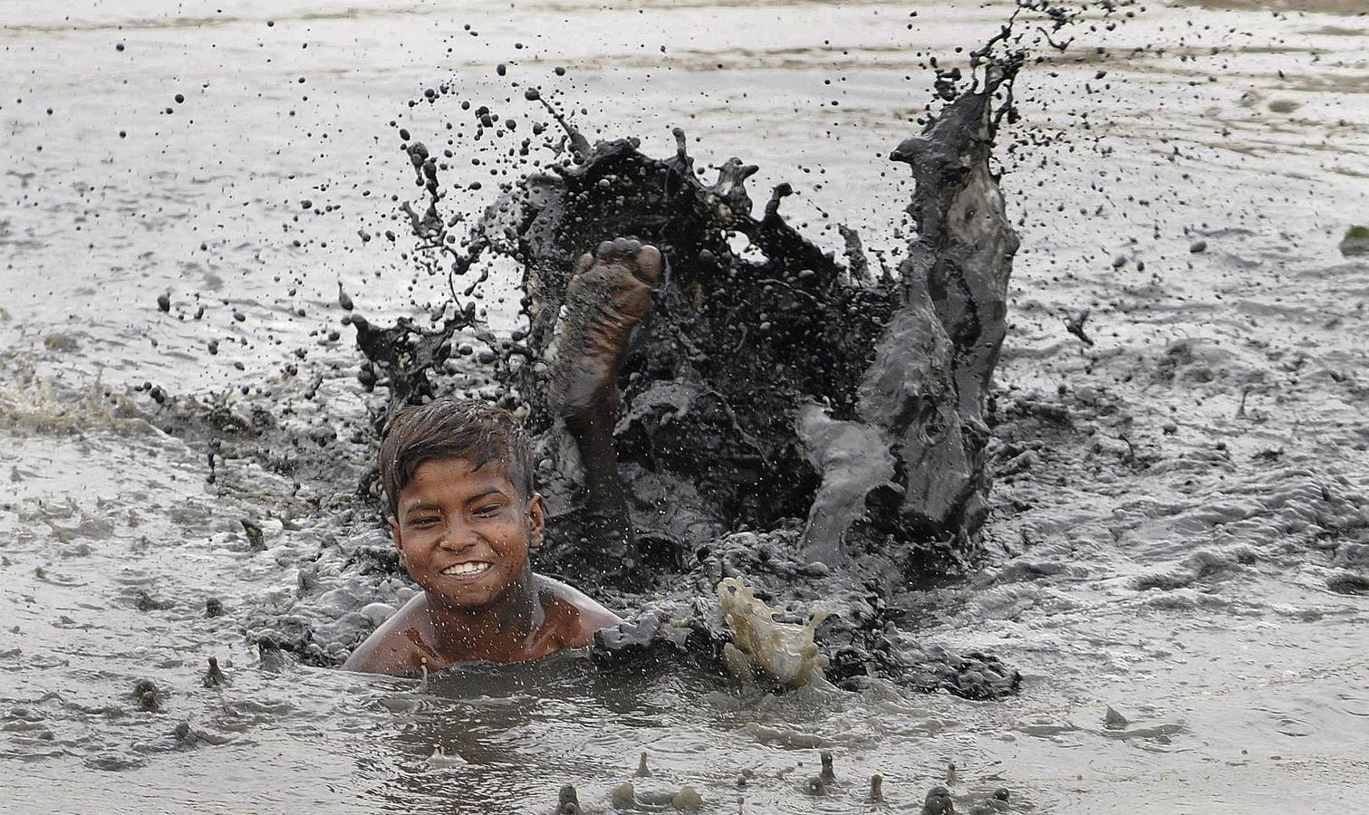 Niño jugando en el agua sucia de un río.