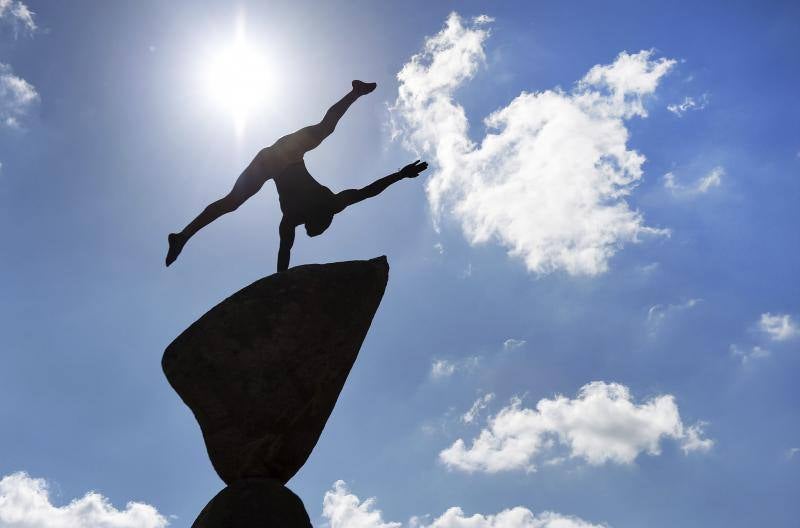 Un gimnasta hace ejercicios de equilibrio en lo alto de una escultura durante la Exposición de Flores de Chelsea