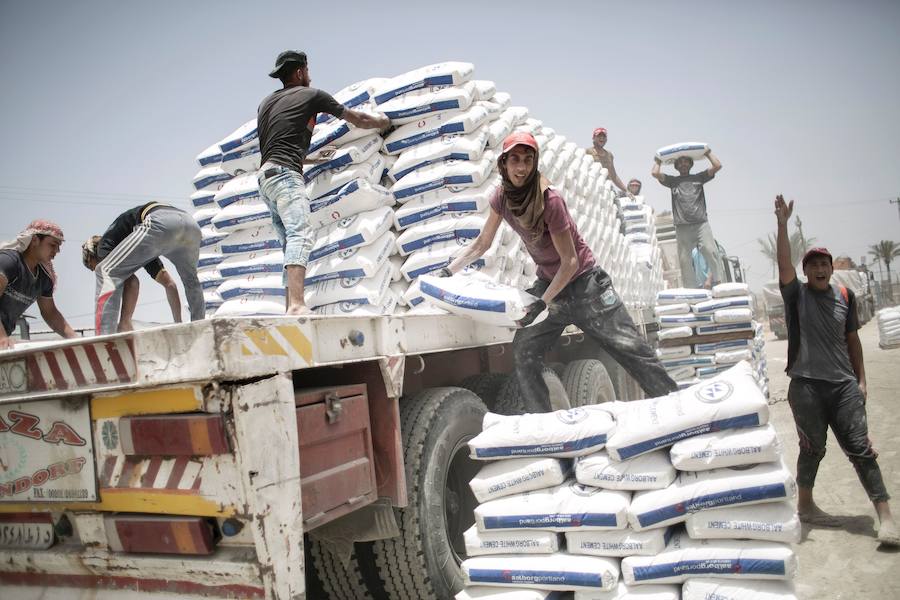 Trabajadores palestinos descargan sacos de cemento de un camión después de entrar en la Franja de Gaza desde Egipto a través del cruce fronterizo de Rafah.