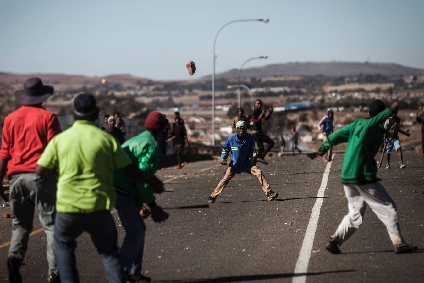 Enfrentamiento a pedradas en una protesta entre dos comunidades por el robo de electricidad en  Ennerdale, un suburbio de Johanesburgo (Sudáfrica). / AFP PHOTO / John WESSELS