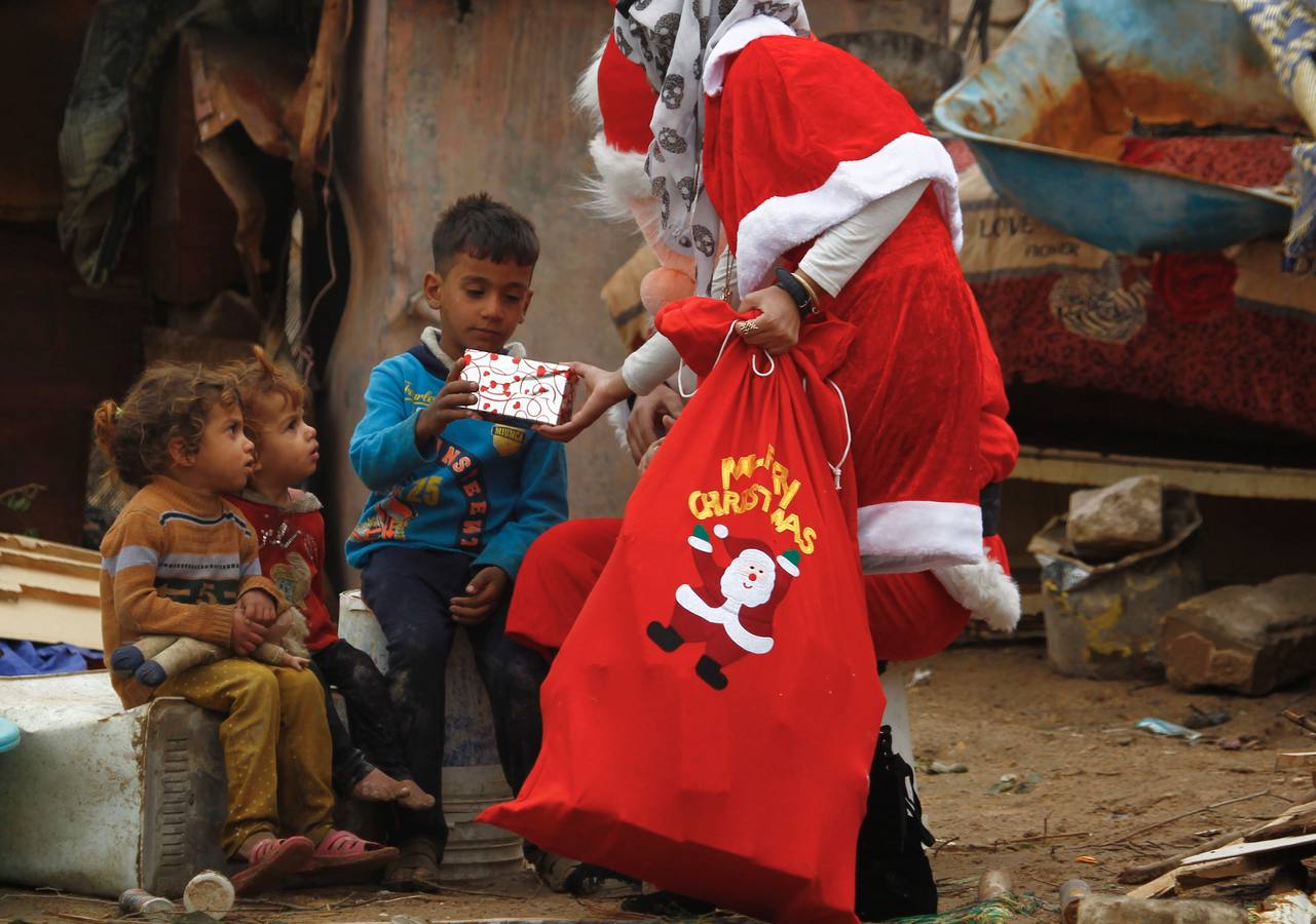 Regalos a niños pobres en Nayaf. Una estudiante de Odontología disfrazada de Santa Claus reparte regalos a los niños pobres en la ciudad chiíta de Nayaf. / AFP PHOTO / Haidar HAMDANI