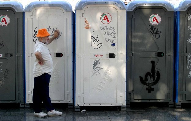 Un hombre espera en unos baños públicos callejeros. 