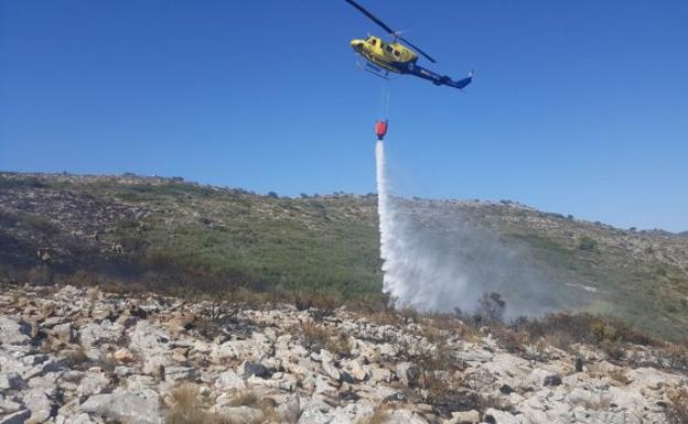 UN helicóptero de extinción, descargando sobre el fuego en el incendio de Teulada-Benissa.