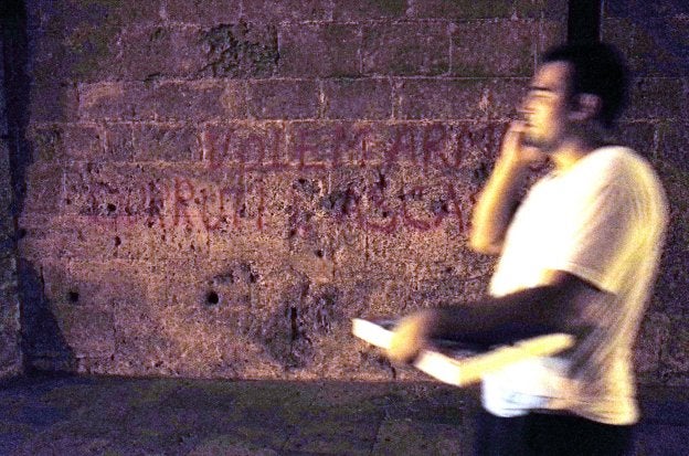 Un hombre pasa ante la pintada realizada en los sillares de las torres de Quart. 