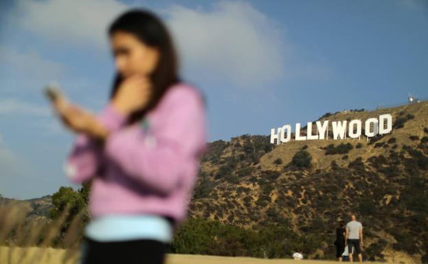 Una mujer usa un teléfono en las cercanías del famoso letrero de 'Hollywood'. 