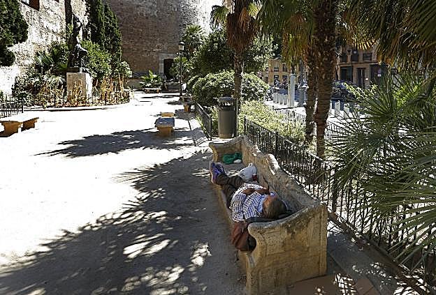 Un indigente duerme junto a las Torres de Quart. 