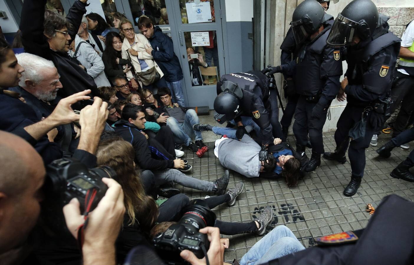Un agente de la policía nacional arrastrando a uno ciudadanos concentrados ante un colegio electoral en Barcelona, durante la celebración del referéndum del 1-O, declarado ilegal por el Tribunal Constitucional.