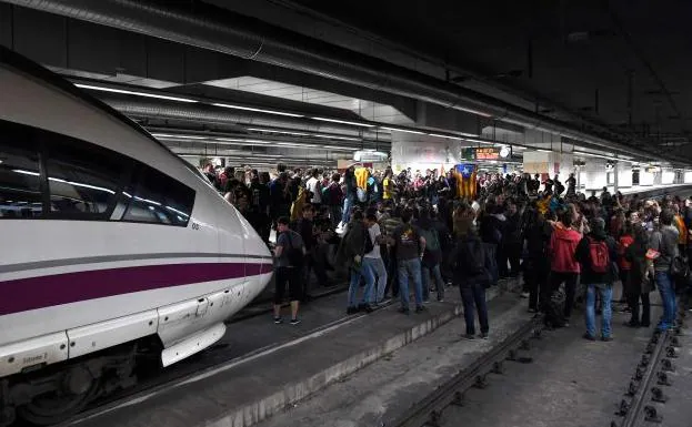 Decenas de personas cortan el paso a un tren en la estación de Sans de Barcelona.