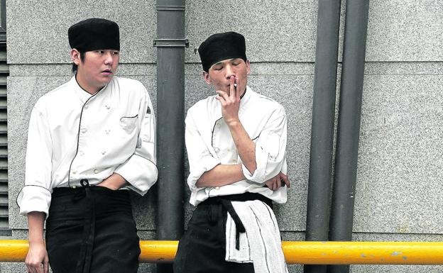 Dos trabajadores japoneses apuran un cigarrillo a la puerta de su empresa.