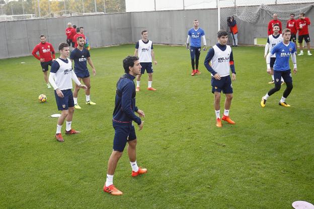 Los jugadores del Valencia, en los compases inciales del entrenamiento en la ciudad deportiva de Paterna.