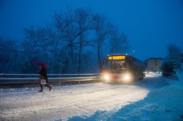 Un peatón y un autobús, ayer, en medio de una nevada. 