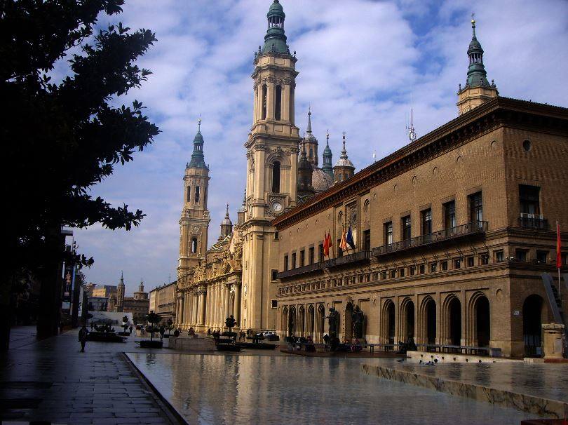 AYUNTAMIENTO DE ZARAGOZA: La plaza del Pilar, en la que se encuentra el ayuntamiento de Zaragoza, combina diferentes elementos, como plantas, esculturas o láminas de agua. Completamente peatonal, este lugar se ha convertido en una zona de recreo para los zaragozanos. En ella destaca un original monumento construido en 1991: la Fuente de la Hispanidad, con una gran inclinación y una cascada imponente.