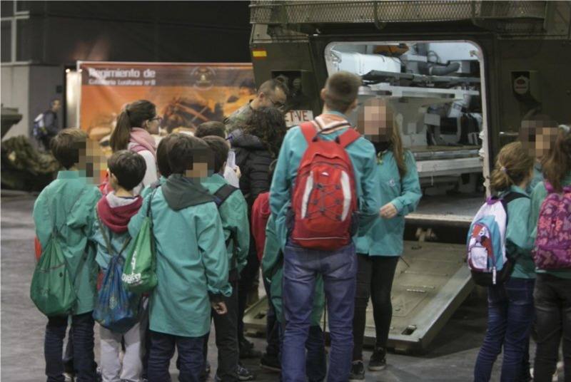 El stand del Ejército, la gran atracción de Expojove. Cientos de niños esperan largas colas para fotografiarse con la bandera de España y el equipamiento militar. Expojove se ha inaugurado este año bajo el lema Nyam! Buena parte de los distintos puestos de las concejalías recreaban huertos, una barraca tradicional o incluso una granja. Como suele ser habitual, las zonas más transitadas son las del Ejército, con representación de la Unidad Militar de Emergencias, el Regimiento de Caballería Lusitania 8 y el Regimiento Número 1 NBQ de Valencia, entre otros. Se han formado largas colas en un puesto que permite a los niños fotografiarse con la bandera de España y equipamiento militar. Al acto de inauguración no ha acudido el alcalde de Valencia, Joan Ribó. La comitiva está presidida por la fallera mayor de Valencia, Rocío Gil, y la fallera mayor infantil, Daniela Gómez, así como por el concejal de Cultura Festiva, Pere Fuset. Tampoco ha acudido ningún concejal de València en Comú y apenas una, Anaïs Menguzzato, del PSPV. La comitiva municipal ha sido recibida en la puerta por un grupo de personas que exigían la desmilitarización de la educación, en protesta por la presencia de las Fuerzas Armadas en la Feria. Ha habido dudas sobre si autorizar o no la presencia del Ejército en Expojove 2017, pero finalmente se autorizó con la condición de que no portaran armas. No están presentes en la feria la Policia Nacional ni la Guardia Civil, que solían recibir muchas visitas en años anteriores. 