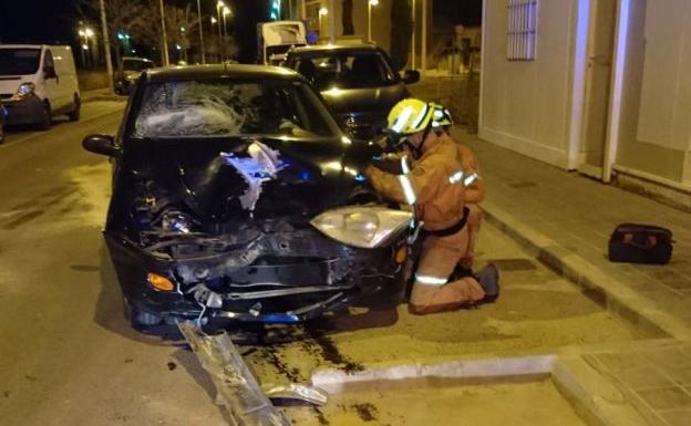 Los bomberos desconectan la batería de un coche tras un accidente de tráfico en Llíria.