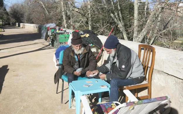 Dos indigentes juegan a las cartas en su asentamiento en las Alameditas. 
