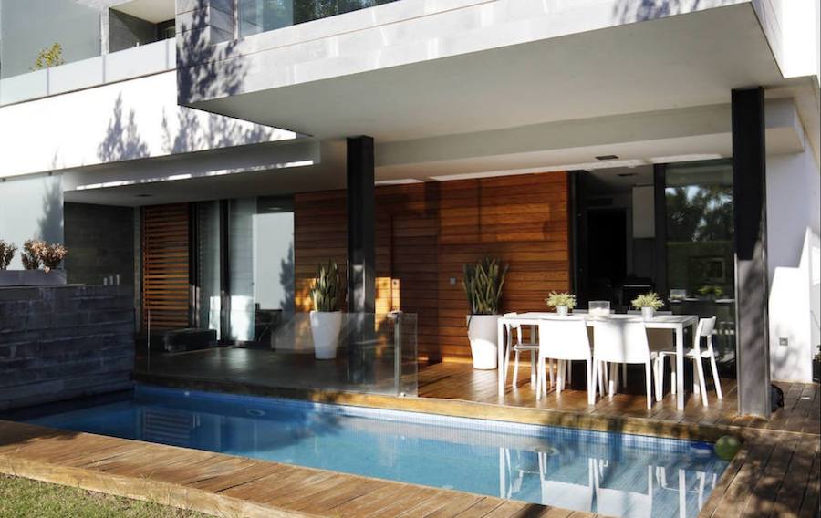 La piscina es una de las protagonistas de la terraza, en la que predomina la madera y la decoración en color blanco.