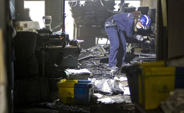 Un policía examina los restos de uno de los juzgados calcinados en el incendio de septiembre. 