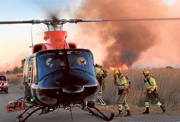 Bomberos suben a un helicóptero durante el incendio de Torreblanca. 