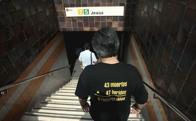 Un miembro de la Asociación de Víctimas del Metro del 3 de Julio desciende a la boca del metro. 