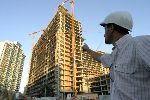 Un hombre señala un edificio en construcción. 