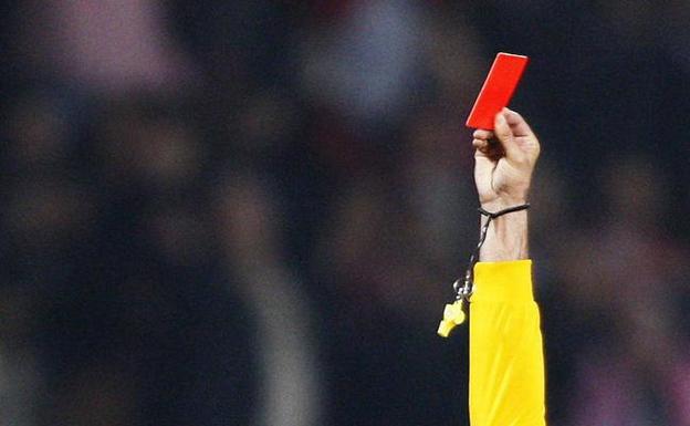 Un árbitro muestra una tarjeta roja en un partido.