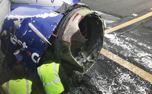 Unos operarios observan el motor siniestrado, poco después del aterrizaje de emergencia.