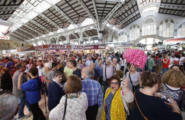 Una guía dirige a un grupo de turistas en el mercado. 