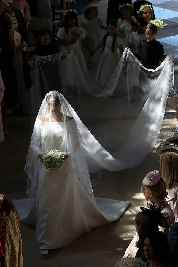 La estadounidense Meghan Markle escogió a la diseñadora británica Clare Waight Keller para su vestido de novia en la boda celebrada hoy en el castillo de Windsor con el príncipe Enrique. Markle lució un diseño muy sencillo, blanco inmaculado con escote de cuello de barco y cubrió su rostro con un velo transparente, adornado con bordados en los bordes hechos de organza y con una cola de cinco metros de longitud. La exactriz adornó su cabeza con una tiara de diamantes, prestada por la abuela del príncipe Enrique, la reina Isabel II.