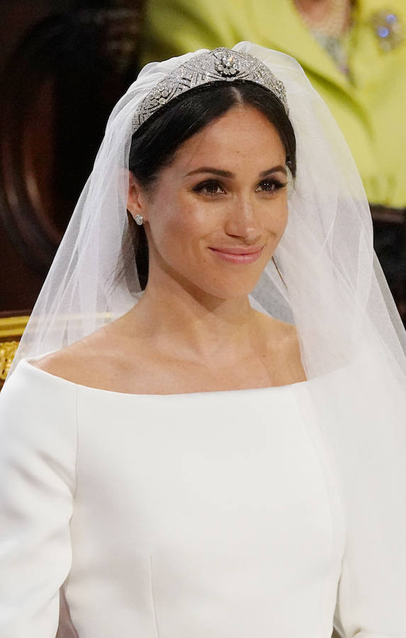 La estadounidense Meghan Markle escogió a la diseñadora británica Clare Waight Keller para su vestido de novia en la boda celebrada hoy en el castillo de Windsor con el príncipe Enrique. Markle lució un diseño muy sencillo, blanco inmaculado con escote de cuello de barco y cubrió su rostro con un velo transparente, adornado con bordados en los bordes hechos de organza y con una cola de cinco metros de longitud. La exactriz adornó su cabeza con una tiara de diamantes, prestada por la abuela del príncipe Enrique, la reina Isabel II.