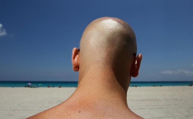 Un hombre calvo, en una playa.