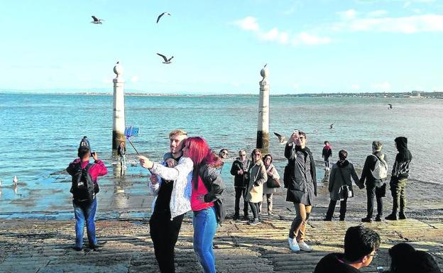 Turistas se fotografían al atardecer en Cais das Columnas, la primitiva puerta de acceso de Lisboa por el Tajo, frente a la plaza del Comercio. 