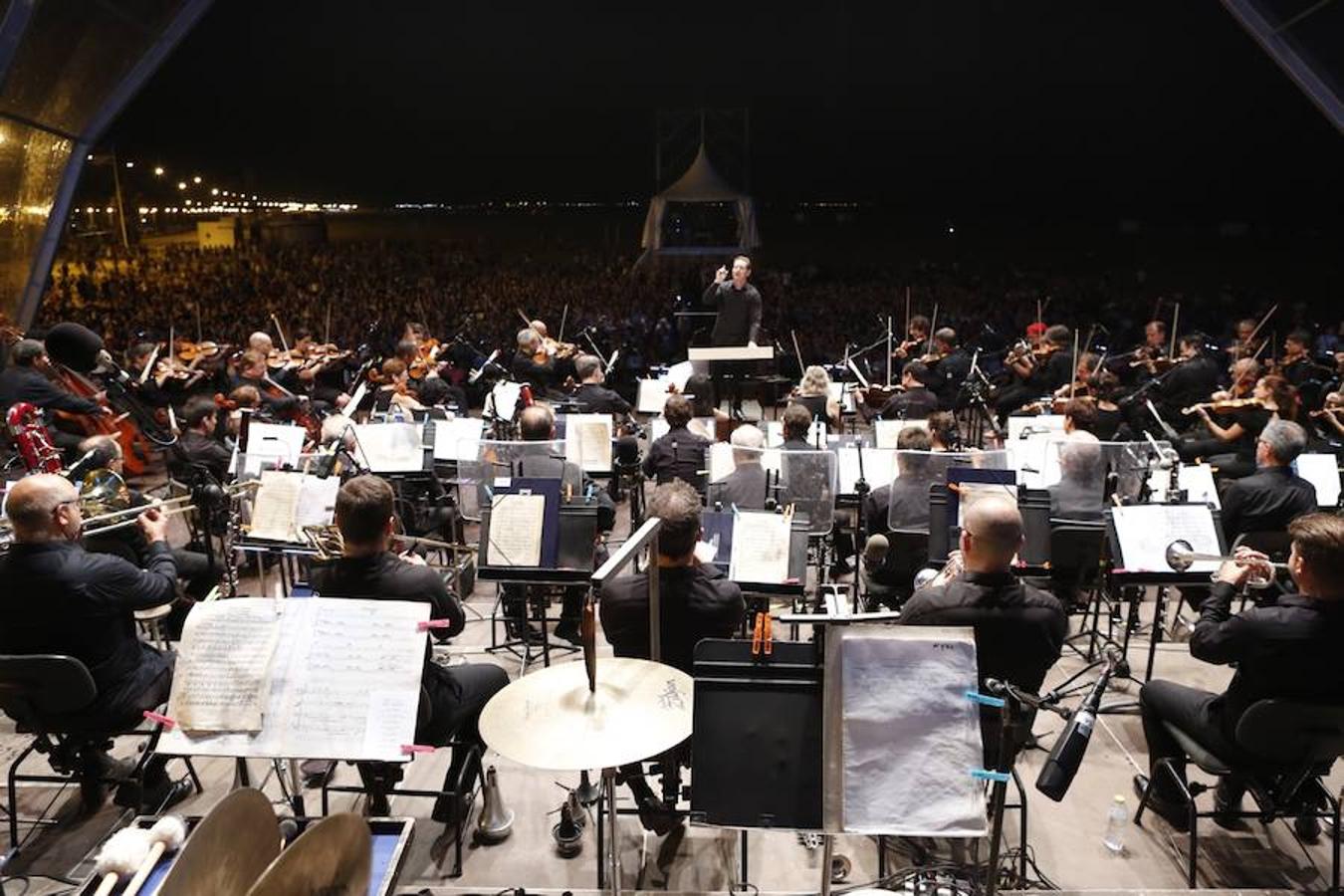 La Orquesta de Valencia hace historia junto al mar. Por primera vez, cierra la temporada en la playa de Las Arenas en un espectáculo para más de 1.000 personas. Un escenario de 300 metros y una cúpula transparente sirve de foco de atracción para el numeroso público congregado en la noche de este viernes en la playa. El concierto se ha bautizado con el nombre de 'Música i Aigua amb l'Orquesta de València'.