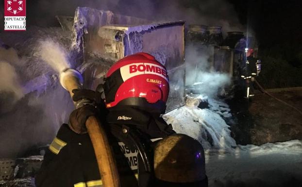 Un bombero trata de sofocar el fuego en el camión incendiado en Nules. 