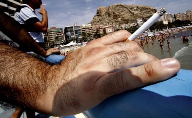 Hombre fumando en una playa de la Comunitat Valenciana.