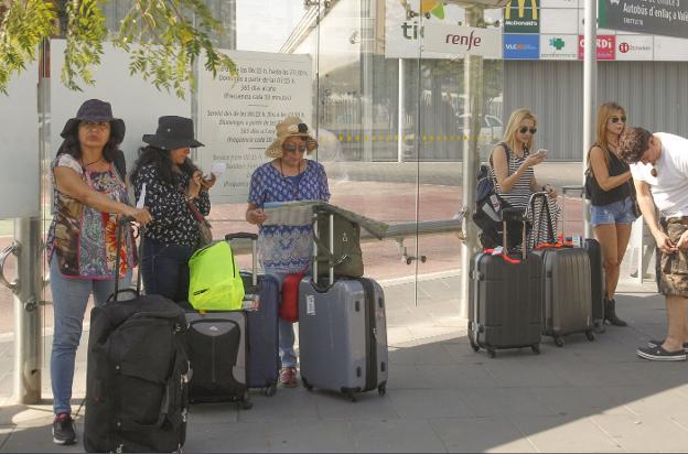 Tres turistas esperan al autobús por la ausencia de taxistas. 