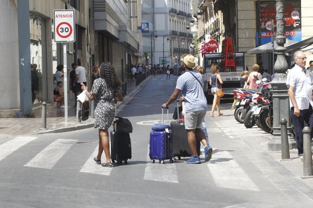 Turistas por las calles de Valencia con sus maletas. 