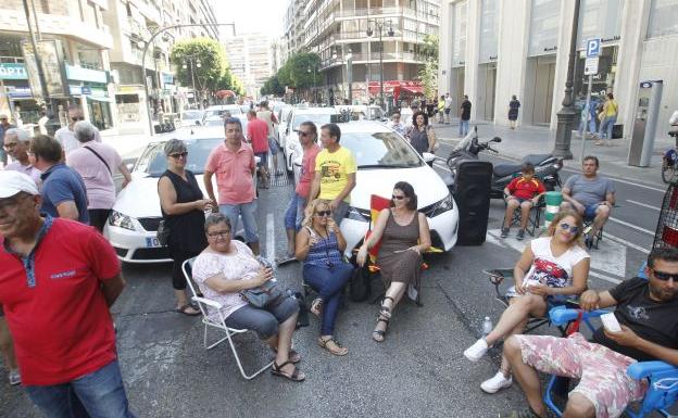 Varios taxistas, junto a sus vehículos en los dos carriles ocupados de la calle Colón.