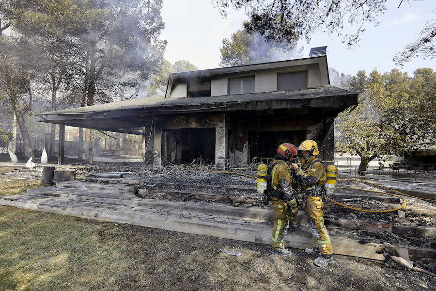 Dos bomberos conversan ante una de las viviendas afectadas por el incendio forestal de Llutxent en la zona de la Marxuqera (Gandía)