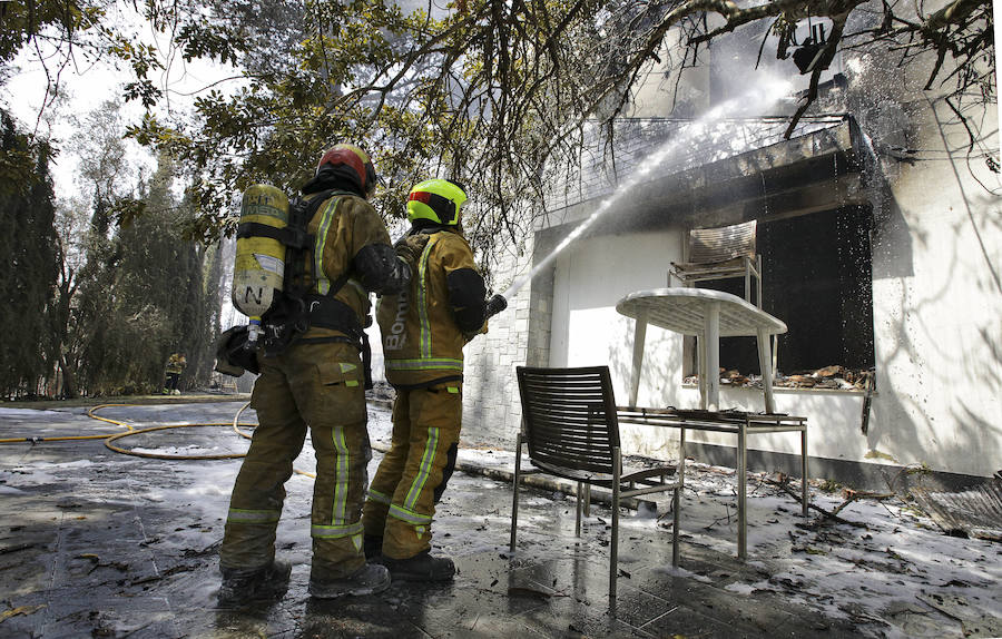 Dos bomberos refrescan el interior de una de las viviendas afectadas por el incendio forestal de Llutxent en la zona de la Marxuqera