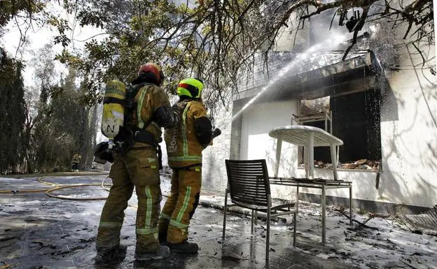 Dos bomberos refrescan el interior de una de las viviendas afectadas por el incendio forestal de Llutxent en la zona de la Marxuqera.