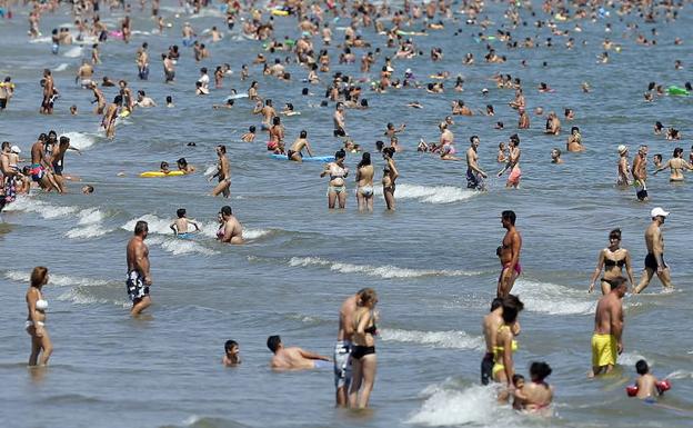 Una playa valencina repleta de personas. 