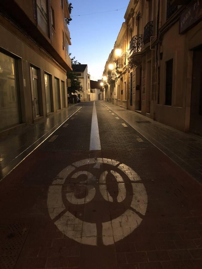 Es una de esas zonas poco conocidas de Valencia. El barrio de Campanar reúne todas esas características que se espera encontrar en un remoto y solitario pueblo, y no en plena urbe. Calles tranquilas, casas antiguas, fachadas con un encanto diseñado por el paso del tiempo. Recorrer sus aceras es pasear por un rincón de paz, ajeno al constante ajetreo de la ciudad. Una especie de paréntesis entre el tráfico, ruido y bullicio, en un lugar donde el reloj parece detenerse, mientras las sombras del atardecer se van colando por cada resquicio. Entre paredes blancas, tonalidades ocre, fuentes y ventanas que se asoman a décadas de historia, permanecen mosaicos en honor a lo que el pueblo fue. Azulejos que recuerdan al oficio hornero y la patrona, la Virgen de Campanar, cuelgan de paredes en las que los ladrillos soportan más años que peso. Casas, unas bajas y otras ilustres, que recuerdan un tiempo no tan lejano, muestras de la Valencia pasada rodeadas de la ciudad actual. 