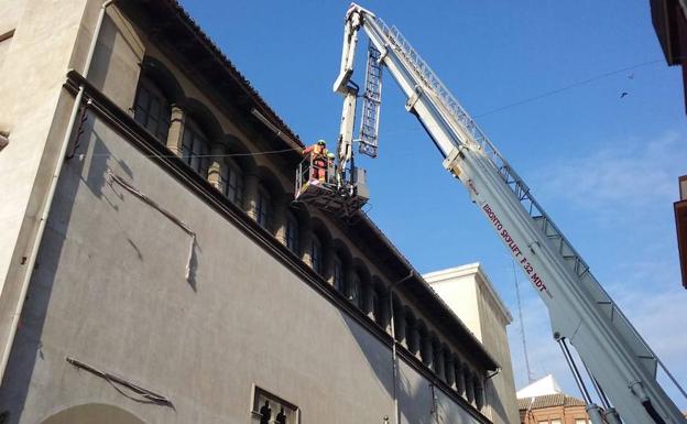 Los bomberos retirando una de las canalizaciones del tejado del Palau Ducal 