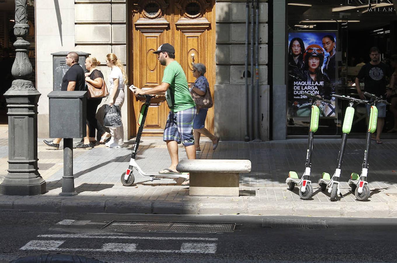 Un usuario de patinete eléctrico en la calle Colón. La ciudad se llena de estos vehículos de movilidad personal y crece la polémica sobre su uso debido al limbo normativo en el que vive Valencia. La convivencia entre vehículos de motor, bicicletas, patinetes y peatones no está siendo fácil. 