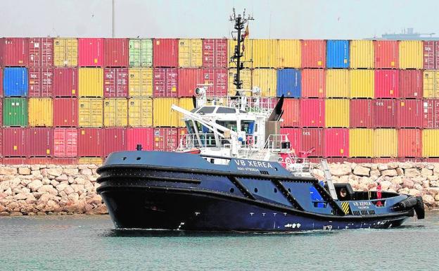 Un remolcador pasa frente a unos contenedores en el Puerto de Valencia. 